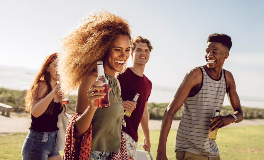 Attractive woman having beer while walking with friends outdoors